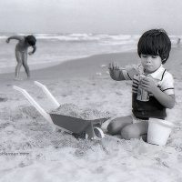 Foto niño jugando con arena en playa