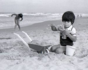 Foto niño jugando con arena en playa